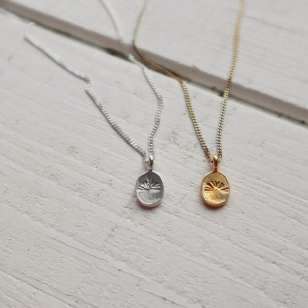 De Solveig ketting met ovalen hanger waarin met de hand een zonsondergang is gemept in zilver of goud.