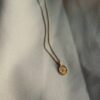 Gouden verfijnde ketting met ovale hanger en gehamerde zonneschijn.