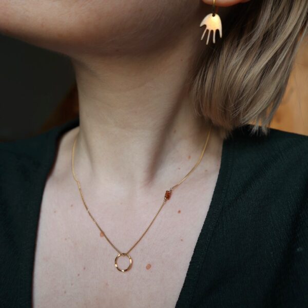 Model met verfijnde gouden ketting met cirkel hanger en hessoniet schijfjes.