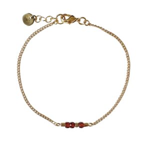 Gouden armband met rode zirkonia glaskralen.