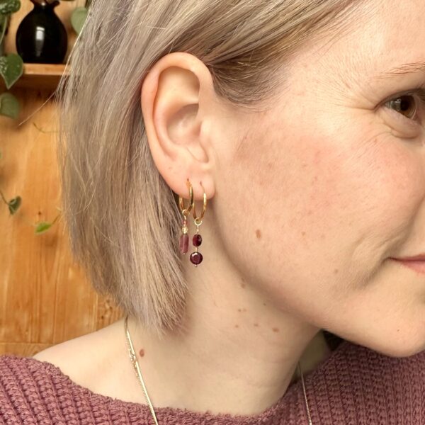 Model met rode granaat en zirkoon oorbellen en ook roze toermalijn oorbellen met rutielkwarts en jade.