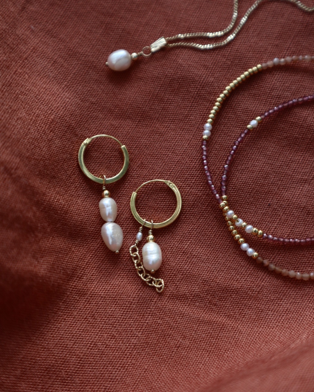 Pareloorbellen, parelketting en een wikkelarmband met edelstenen.