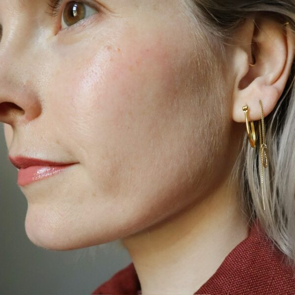 Blond model met ovalen gouden Luz oorbel en gouden doortrekoorbel Rio met gedraaide ring