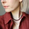 Blond model met een ketting van edelsteen chipjes in robijn.