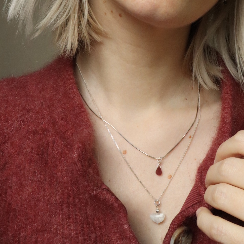 Marit met een sterling zilveren kettingenset. Ze draagt Rani met een druppeltje van rood granaat en Mona met een liggende halve maan van maansteen.