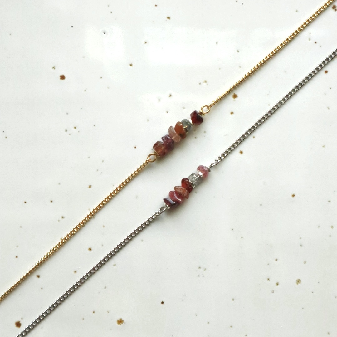 Zilver en goudkleurige schakelarmbanden met in het midden meerkleurige saffier.