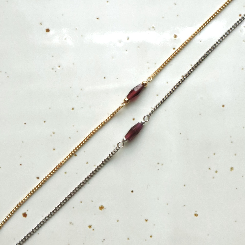 Zilver en goudkleurige schakelarmbanden met in het midden een ruitje van rode granaat.