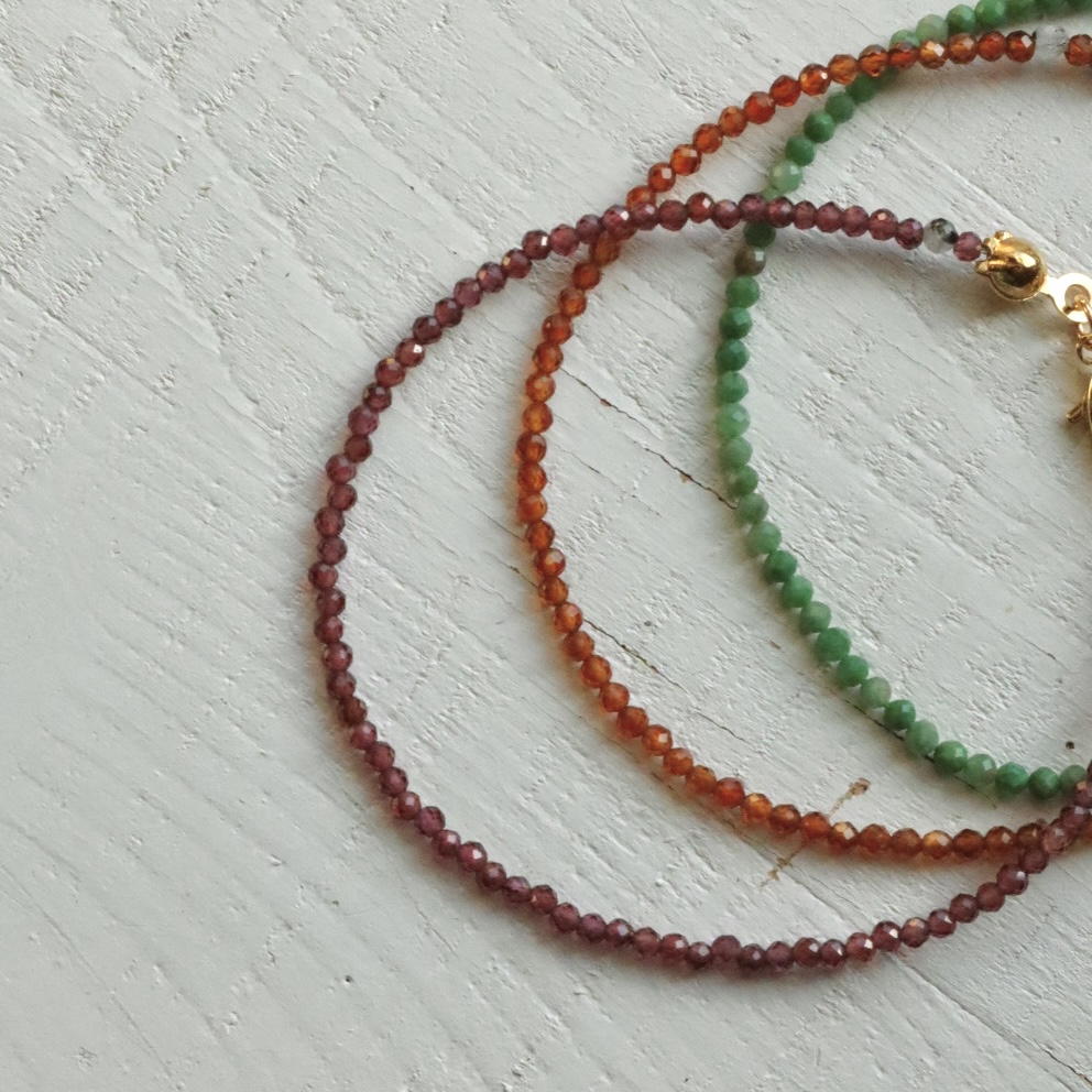 Drie soorten kralenarmbanden van “Dottie” paarse granaat, oranje granaat en groene jade.
