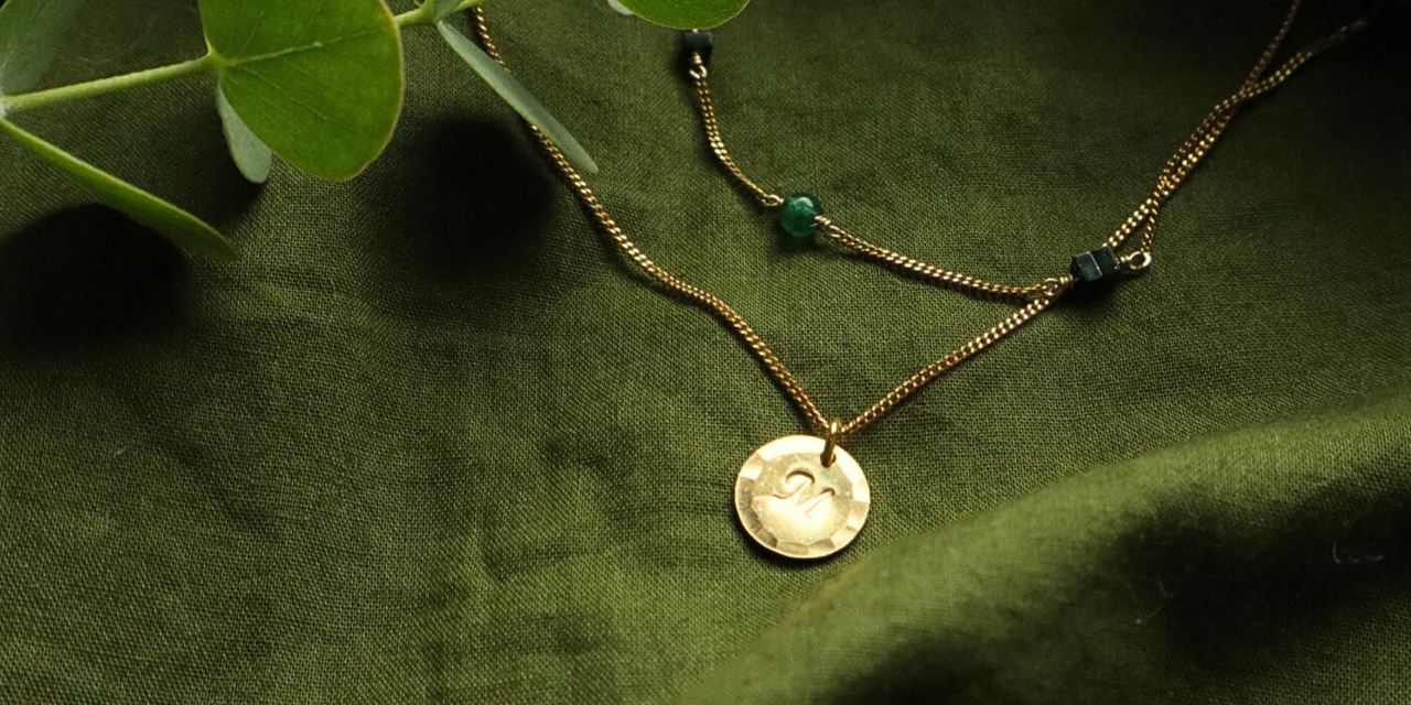 Groene ondergrond met twee gouden kettingen. Miren en Sage 