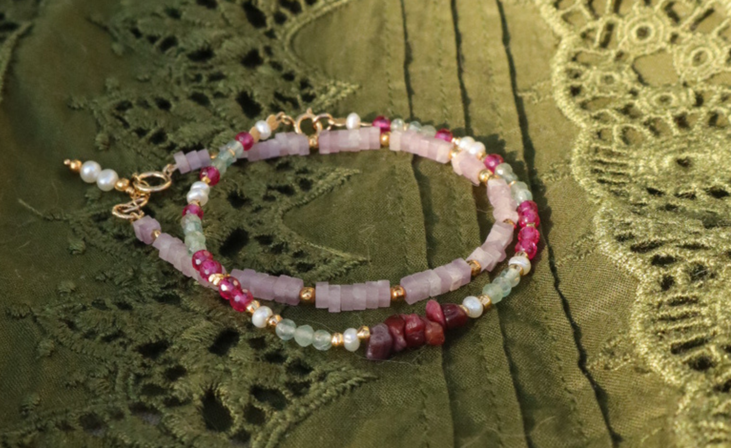 Twee kralenarmbanden met lila, roze en groene edelstenen. 